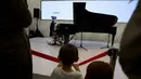 Seorang anak melihat permainan piano dari robot "Teotronico" dalam acara Konferensi Robot Dunia 2017 di Beijing, 23 Agustus 2017. Selain bisa memainkan piano, robot rancangan Matteo Suzzi ini juga dapat menyanyikan lagu-lagu populer. (AP/Ng Han Guan)