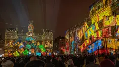 Orang-orang melihat balai kota Lyon (tengah) dan alun-alun Place des Terreaux yang diterangi cahaya lampu selama Festival of Lights (Fete des Lumieres) di kota Lyon, Prancis, Kamis (5/12/2019). Festival Cahaya ini merupakan salah satu kegiatan yang paling terkenal di Lyon. (ROMAIN LAFABREGUE / AFP)