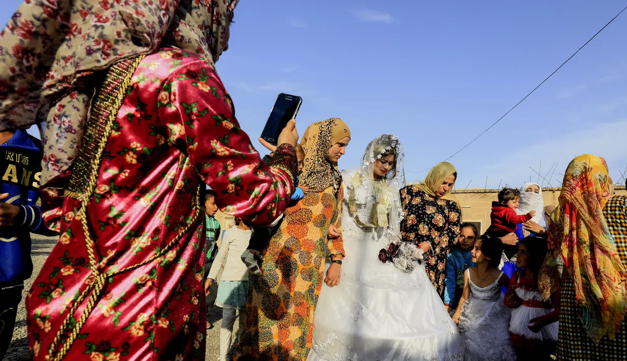 Mempelai wanita, Heba mengenakan gaun pengantin putih serta dikalungi uang saat prosesi pernikahan di Raqqa, Suriah (27/10). Kini ISIS sudah berhasil ditumpas dari Kota Raqqa. (AFP Photo/Delil Souleiman)