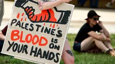 Seorang demonstran dengan membawa papan tanda bergabung dengan yang lain di luar gedung Parlemen menjelang pertemuan antara Perdana Menteri Australia Anthony Albanese dan Presiden Israel Isaac Herzog di Canberra pada Rabu 11 Februari 2026. Kunjungan resmi Presiden Israel, Isaac Herzog, ke Australia memicu gelombang unjuk rasa pro-Palestina di berbagai kota besar seperti Sydney, Melbourne, dan Canberra. (DAVID GRAY/AFP)