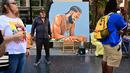 Artis Mohammed Mubarak berdiri di samping karya seni mendiang rapper AS Nipsey Hussle saat orang-orang berkumpul untuk upacara Anumerta Hollywood Walk of Fame Star Hussle di Hollywood, California (15/8/2022). (AFP/Frederic J. Brown)