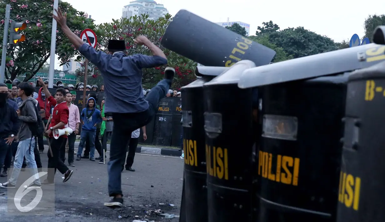 Seorang mahasiswa menendang tameng polisi yang berjaga saat unjuk rasa di Jalan Medan Merdeka Barat, Jakarta, Kamis (20/10). Mahasiswa menagih janji Nawacita pemerintahan Jokowi-JK. (Liputan6.com/Gempur M Surya)