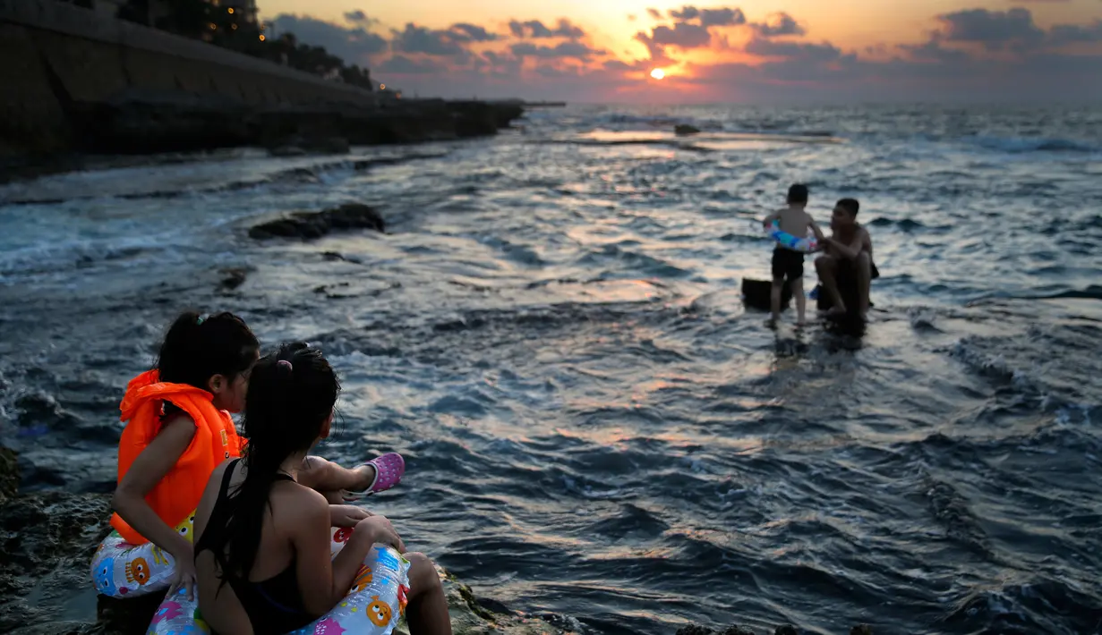 Dua anak menikmati matahari terbenam saat berenang di Laut Mediterania dari Corniche, atau promenade tepi laut  pada hari terakhir musim panas, di Beirut, Lebanon (20/9). (AP Photo / Hussein Malla)