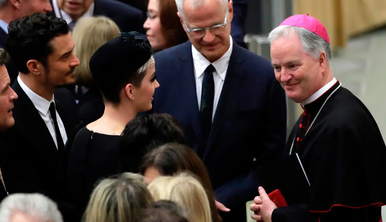 Katy Perry bersama Orlando Bloom berbincang dengan Sekretaris Dewan Kepausan untuk Kebudayaan uskup Paul Tighe pada akhir audiensi oleh Paus Francis di aula Paul VI, Vatikan, (28/4). (AP Photo / Alessandra Tarantino)