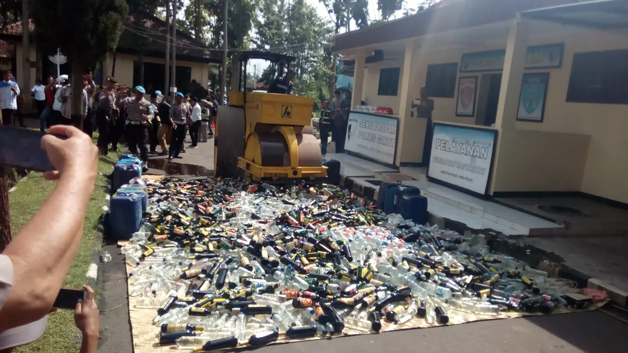 Nampak alat berat tengah memusnahkan ribuan botol miras hasil razia polres Garut