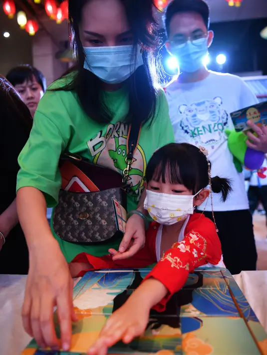 Seorang anak didampingi orang tua bermain puzzle dalam acara perayaan Festival Pertengahan Musim Gugur di Museum Hainan, Haikou, ibu kota Provinsi Hainan, China selatan (1/10/2020). (Xinhua/Guo Cheng)