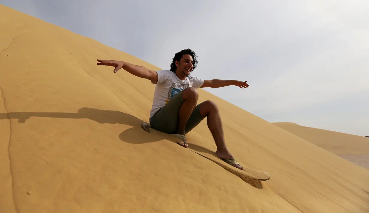 Ekspresi sorang pria saat menikmati berseluncur di gurun pasir Wadi el-Rayan Fayoum, Mesir (18/11). Di gurun ini menyajikan banyak hiburan dan pariwisata salah satunya, berseluncur di pasir atau sandboarding. (Reuters/Mohamed Abd El Ghany)