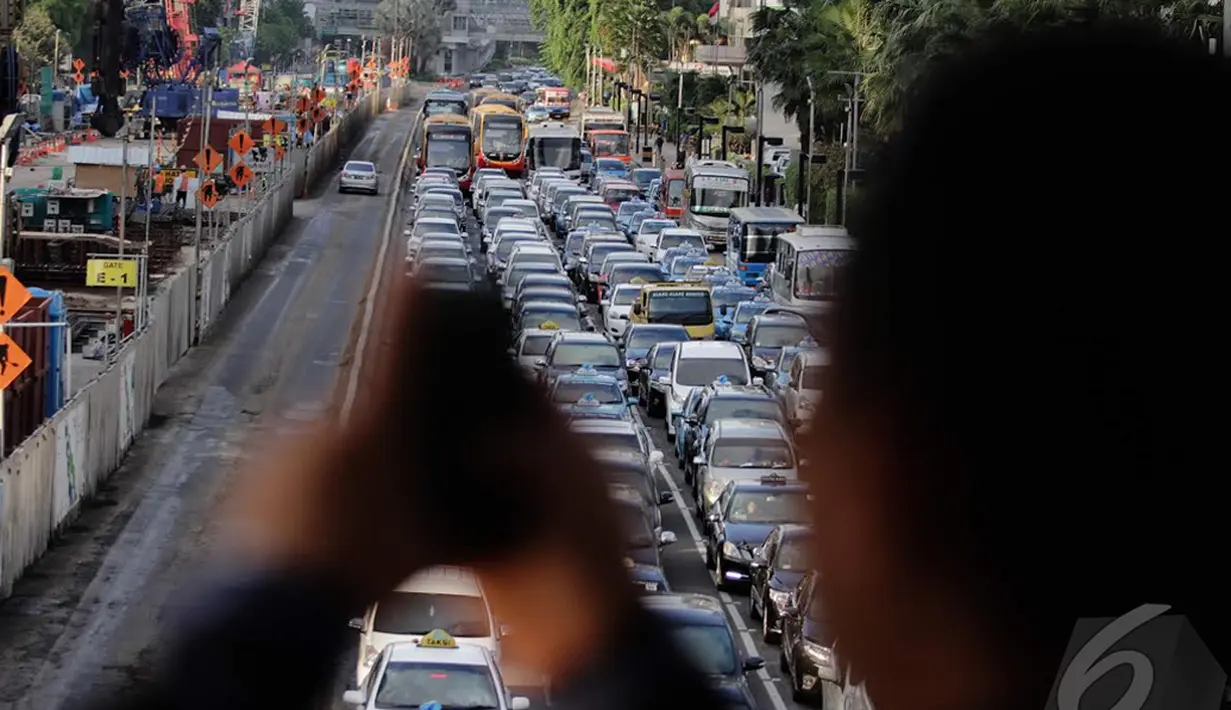 Salah seorang pejalan kaki saat mengabadikan kemacetan di Jl MH Thamrin, Jakarta, Kamis (18/12/2014). (Liputan6.com/Faizal Fanani)