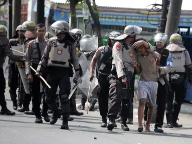 Polisi menangkap seorang pria saat tarjadi bentrok dengan massa di kawasan Petamburan, Jakarta Barat, Rabu (22/5/2019). Kapolres Metro Jakarta Barat Kombes Hengki Haryadi mengatakan ada 99 orang diamankan di Polres Jakarta Barat dan Polda Metro Jaya. (Liputan6.com/Faizal Fanani)