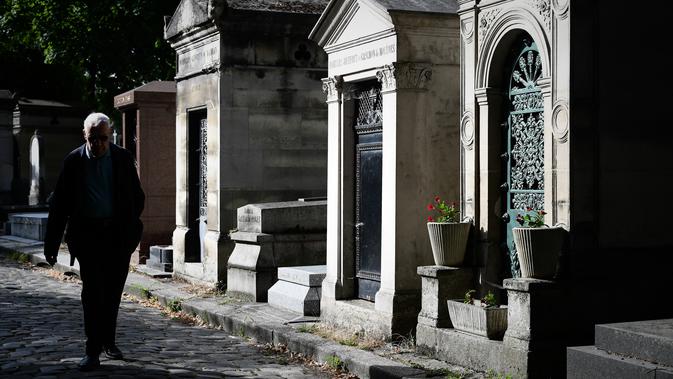 Seorang pria berjalan melewati kuburan di pemakaman Pere Lachaise di Paris (22/7/2019). Pemakaman ini paling banyak didatangi wisatawan di dunia. Artis dan banyak tokoh terkenal dimakamkan di sini. (AFP Photo/Philippe Lopez)
