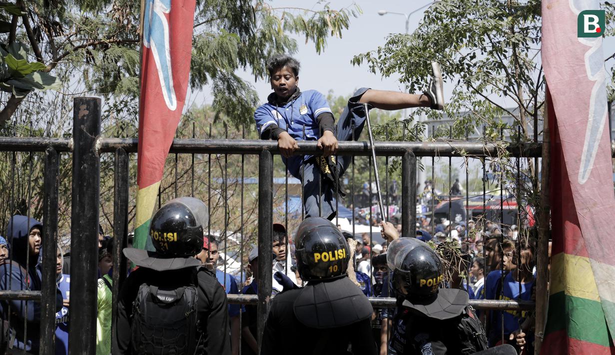 Petugas kepolisian menghalau suporter yang memanjat gerbang masuk Stadion GBLA, Jawa Barat, Minggu (23/9/2018). Pengamanan jelang laga Persib Bandung kontra Persija Jakarta diperketat. (Bola.com/M Iqbal Ichsan)