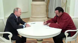 Aktor AS, Steven Seagal menandatangani paspor miliknya yang diberikan Presiden Vladimir Putin di Kremlin di Moskow, Rusia,(25/11). Diketahui Steven mempunyai hubungan dekat dengan Vladimir Putin dan Rusia. (Sputnik/Kremlin/Alexei Druzhinin via REUTERS)