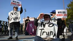 Para demonstran Korea Selatan yang mengenakan spanduk bertuliskan "Tolak Trump" memegang plakat selama demonstrasi yang mengecam tekanan Presiden AS Donald Trump untuk meningkatkan investasi Korea Selatan di AS, di Gyeongju pada 29 Oktober 2025, menjelang KTT Kerja Sama Ekonomi Asia-Pasifik (APEC). (Jung Yeon-je/AFP)