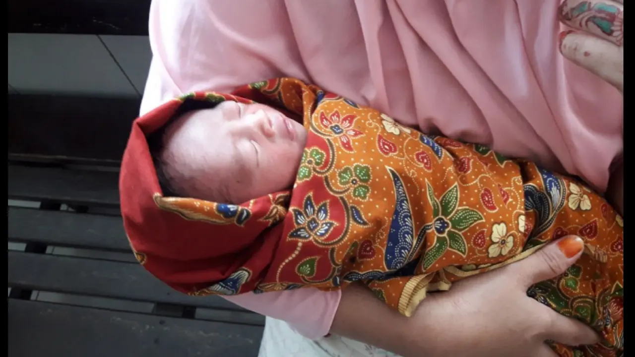 Bayi tampan saat digendong oleh istri dari salah, wrong tukang ojek yang menemukannya (Fauzan/Liputan6.com)