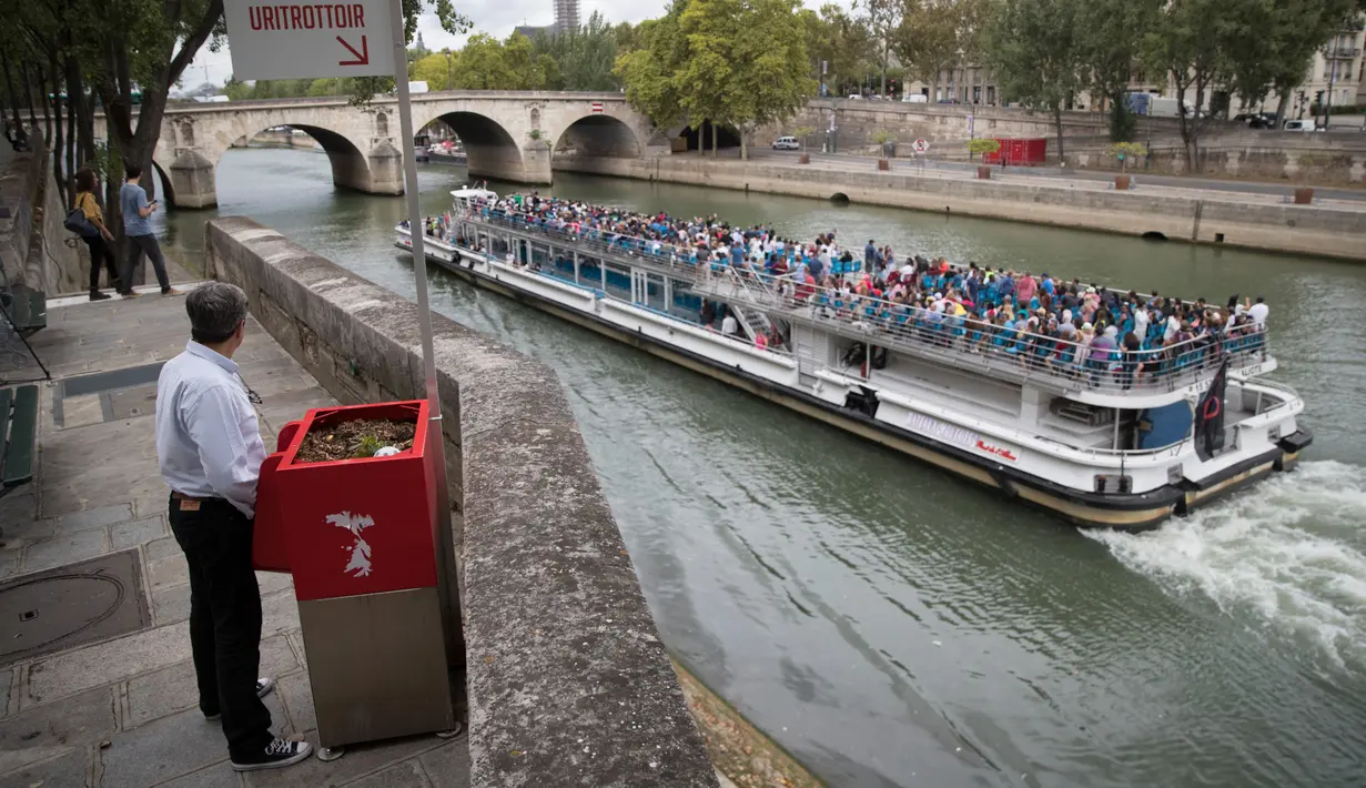 Seorang pria berdiri di depan kotak pembuangan urin yang disediakan pemerintah kota di Saint-Louis, Paris, 13 Agustus 2018. Digadang sebagai alat ramah lingkungan, kotak itu menjadi tempat buang air kecil bagi pria alias urinoir. (AFP/Thomas SAMSON)
