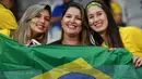 Tiga fans wanita tersenyum sambil memegang bendera Brasil sebelum pertandingan melawan Argentina pada semifinal Copa America 2019 di Stadion Mineirao (2/7/2019). Di pertandingan ini Brasil menang 2-0 atas Argentina berkat gol striker Gabriel Jesus dan Roberto Firmino. (AFP Photo/Nelson Almeida)