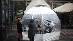 Sejumlah orang menyantap makanan di sebuah dining bubble, instalasi tempat makan berbentuk gelembung, di luar ruangan di Yerusalem pada 26 November 2020. Tempat makan di luar ruangan menjadi langkah yang diadopsi secara luas oleh banyak restoran untuk mengatasi pandemi COVID-19 (Xinhua/Muammar Awad)