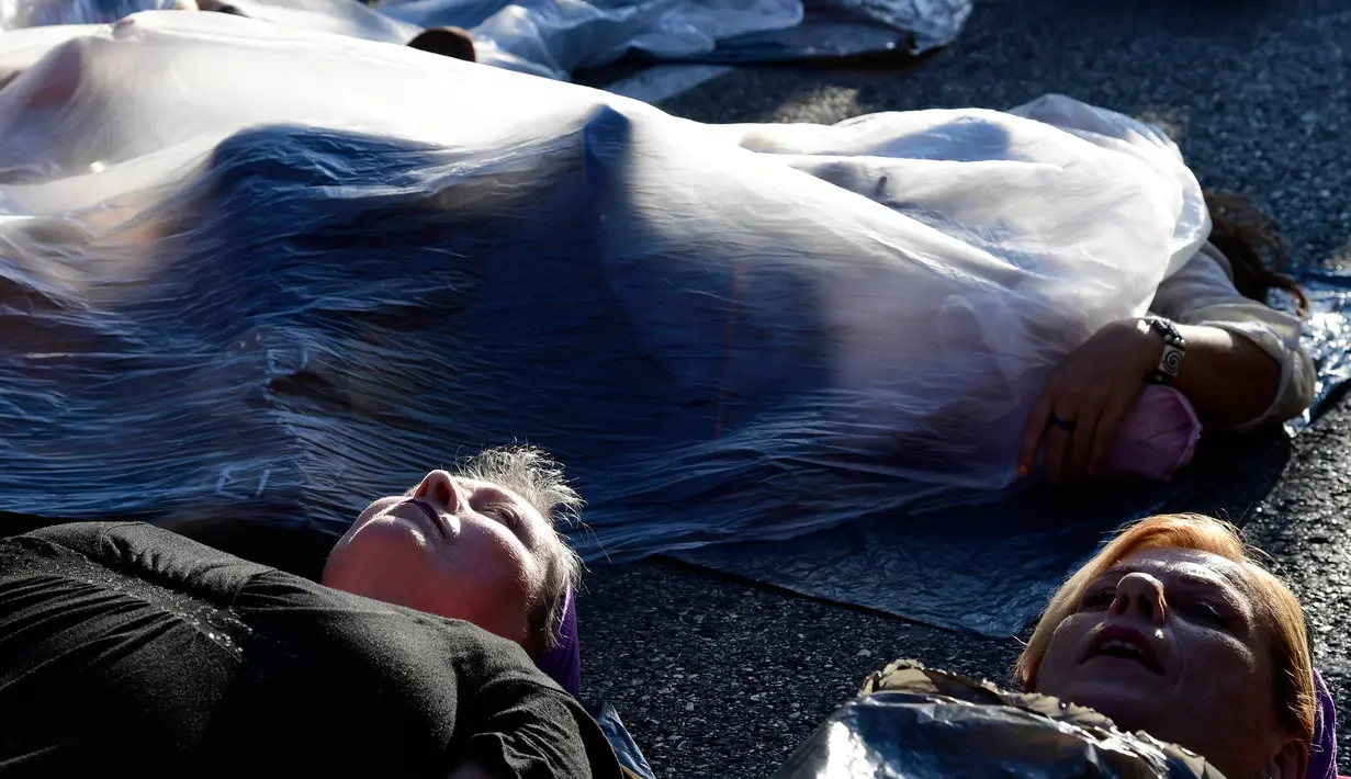 Sejumlah wanita berbaring dan membungkus diri dengan plastik saat melakukan aksi di Madrid, Spanyol (16/5). Dalam aksinya mereka menutup tubuhnya dengan plastik dan berbaring di jalanan. (AFP/Javier Soriano)