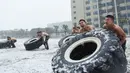 Polisi militer China mengangkat ban saat sesi pelatihan di tengah hujan salju di Hefei, Provinsi Anhui, China (15/1/2020). Latihan fisik yang dilakukan anggota polisi militer China meliput angkat ban traktor sampai dengan teknik menyerang dengan menggunakan senapan berpisau. (AFP Photo/Str/China Out