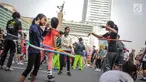 Anak-anak bermain permainan tradisional hula hoop ditemani sejumlah mahasiswa dari Penggerak Olahraga saat car free day (CFD) di kawasan Bundaran HI, Jakarta, Minggu (14/7/2019). Kegiatan yang rutin digelar ini bertujuan mengajak masyarakat DKI Jakarta aktif berolahraga. (Liputan6.com/Faizal Fanani)