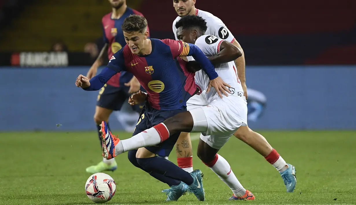 Pemain Barcelona, Gavi (tengah kiri) berusaha melewati penjagaan pemain Sevilla, Albert-Mboyo Sambi Lokonga pada laga lanjutan Liga Spanyol 2024/2025 yang berlangsung di Estadi Olimpic Lluis Companys, Barcelona, Spanyol, Senin (21/10/2024) dini hari WIB. (AFP/Josep Lago)