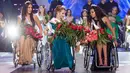Miss Belarus Aleksandra Chichikova (tengah) terpilih sebagai Miss Wheelchair World di Warsawa, Polandia, Sabtu (7/10). Para kontestan berlaga dengan membawakan baju nasional, gaun cocktail dan gaun malam juga menampilkan tarian. (Wojtek Radwanski/AFP)