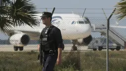 Petugas melakukan penjagaan di dekat pesawat EgyptAir, yang membawa 55 penumpang dan tujuh kru, di Bandara Larnaca, Selasa (29/3). Pesawat yang bertolak dari Alexandria menuju Kairo itu dibajak dan dipaksa mendarat di Siprus. (REUTERS/Yiannis Kourtoglou)