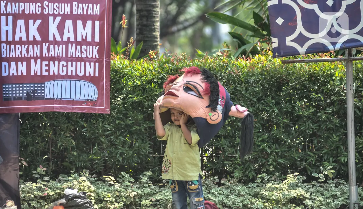 Seorang anak mengenakan kostum badut saat ikut dalam aksi di depan Balai Kota DKI Jakarta, Kamis (1/12/2022). Sebelumnya, PT JakPro mengatakan harga sewa Kampung Susun Bayam di dekat Jakarta Internasional Stadium (JIS) disesuaikan menggunakan Pergub Nomor 55 Tahun 2018. JakPro menyebut tarif tertinggi rusun tersebut Rp765 ribu per bulan. (merdeka.com/Iqbal S Nugroho)