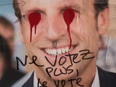 Poster Capres Prancis,  Emmanuel Macron terlihat rusak di Paris, Selasa (2/5). Sejumlah poster capres Prancis lainnya juga tampak rusak yang diduga dilakukan oleh orang yang tidak suka dengan mereka. (AFP PHOTO / JOEL SAGET)