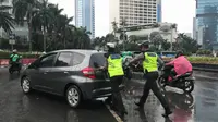 Dua anggota Polisi Lalu Lintas mendorong sebuah mobil Honda Jazz di kawasan Bundaran HI, Jakarta, Selasa (30/1/2018). (Facebook Felicia Siahaan)