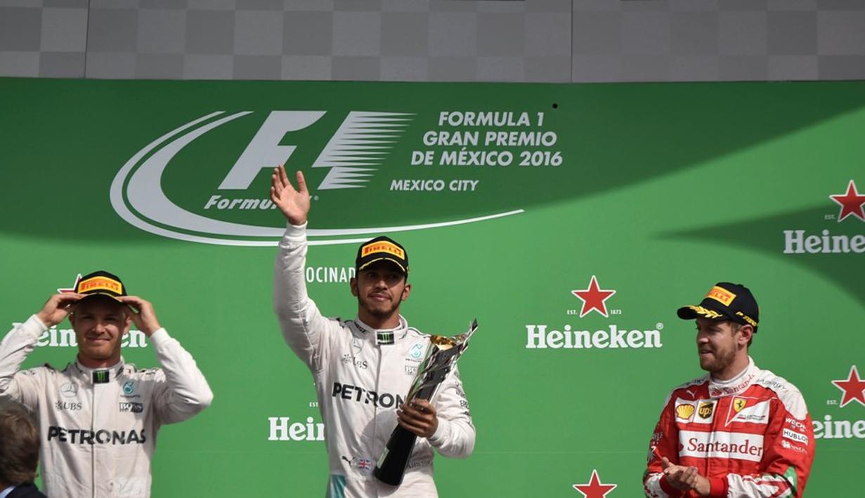 Pebalap Mercedes, Lewis Hamilton, berpose dengan trofi juara F1 GP Meksiko di Sirkuit Autodromo Hermanos Rodriguez, Senin (31/10/2016) dini hari WIB. Peringkat kedua, Nico Rosberg dan ketiga Sebastian Vettel. (AFP/Yuri Cortez)
