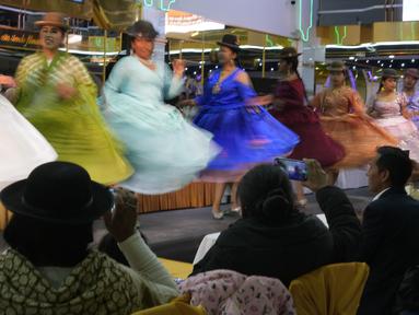 Model perempuan Aymara mengenakan kreasi desainer lokal pada peragaan busana Cholita di El Alto, Bolivia, Rabu (18/5/2022). Memodelkan selimut warna-warni, topi bowler, rok dan perhiasan, di antara busana lainnya, para model yang merupakan penduduk asli tersebut berjalan di atas catwalk untuk mendongkrak perekonomian puluhan perajin dan desainer yang terkena dampak lebih dari dua tahun pembatasan COVID-19. (AP Photo/Juan Karita)