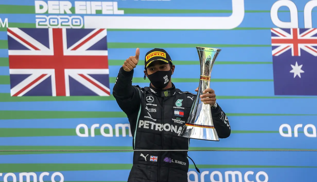 Pembalap Mercedes Lewis Hamilton memegang trofi setelah memenangkan F1 GP Eifel di Nuerburgring, Nuerburg, Jerman, Minggu (11/10/2020). Hamilton dengan 91 kemenangannya menyamai legenda F1 Michael Schumacher. (Wolfgang Rattay, Pool via AP)