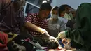 Dokter hewan dan mahasiswa saat melakukan operasi amputasi beruang madu di Banda Aceh (14/6/2019). Anak beruang madu yang diperkirakan berusia 2 tahun lebih tersebut harus diamputasi akibat terkena jerat babi. (AFP Photo/Chaideer Mahyuddin)