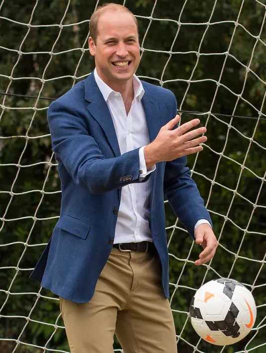 Pangeran William bereaksi melihat bola yang hampir masuk ke gawangnya saat bermain bersama anak-anak program pendidikan sepak bola wanita Inggris, Wildcats Girls, di Kensington Palace, London, Kamis (13/7). (Dominic Lipinski / POOL / AFP)