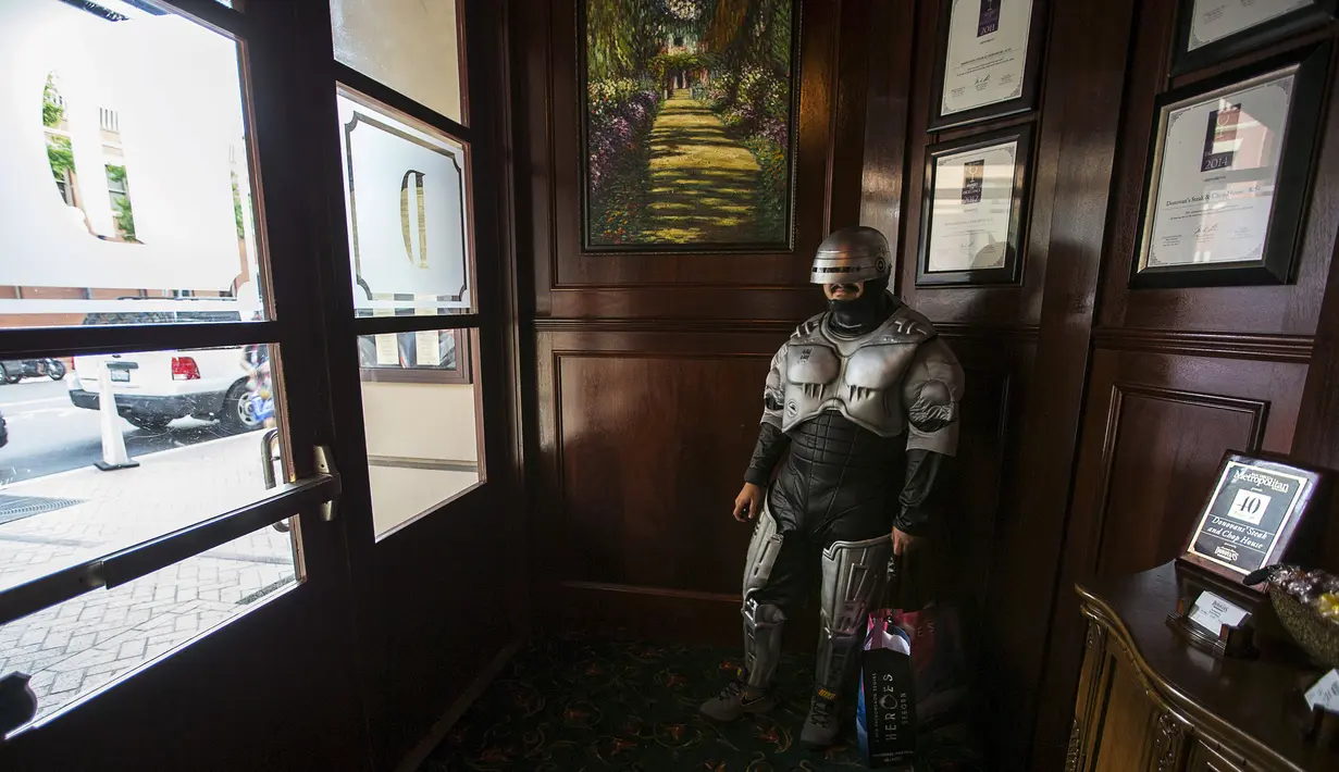 Pehobi mengenakan kostum berkarakter Robocop menunggu di sebuah restoran saat Comic-Con International Convention 2015 di San Diego, Kalifornia, Amerika, (9/7/2015). Acara ini pertama kali dihelat pada tahun 1970. (REUTERS/Mario Anzuoni)