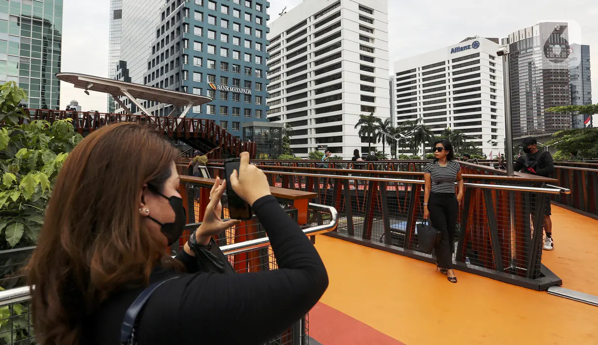 Warga berpose saat difoto dengan kamera ponsel di Jembatan Penyeberangan Orang (JPO) Pinisi, Jalan Jenderal Sudirman, Karet, Jakarta, Selasa (15/3/2022). Keberadaan JPO Pinisi langsung disambut baik oleh warga dengan ramai-ramai berkunjung untuk sekadar melakukan swafoto. (Liputan6.com/Johan Tallo)