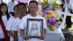 Keluarga korban bom gereja Surabaya membawa foto Martha Djumani pada pemakaman di komplek Taman Makam Keputih, Surabaya, Rabu (16/5). Martha merupakan korban bom bunuh diri di Gereja Pantekosta Pusat Surabaya Minggu (13/5) lalu. (AP/Achmad Ibrahim)