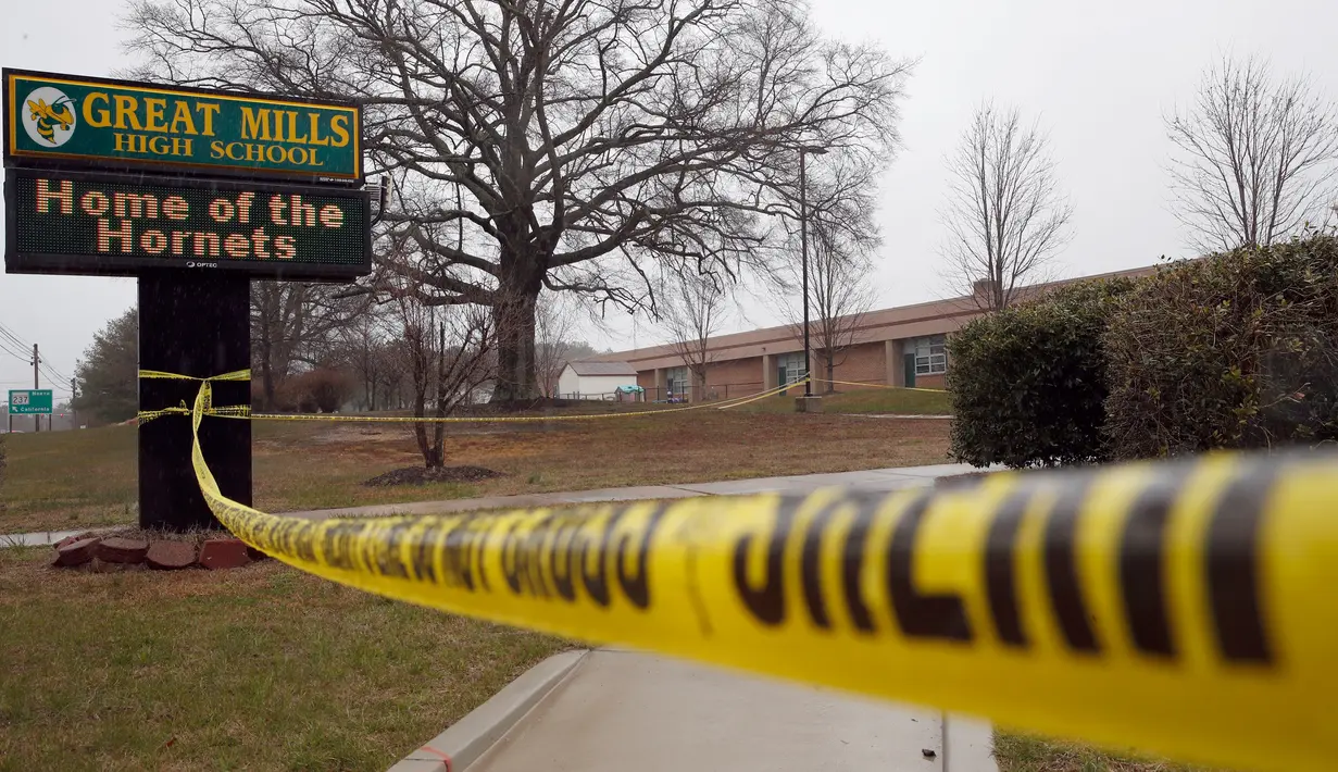 Garis polisi dipasang di sekitar lokasi penembakan di Great Mills High School di Maryland, AS (20/3). Pelaku berusia 17 tahun bernama Austin Wyatt Rollins akhirnya tewas ditembak petugas keamanan. (AP Photo / Alex Brandon)