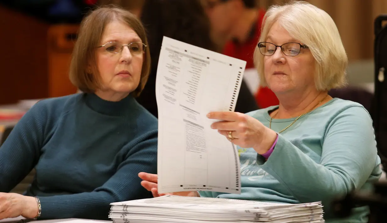 Petugas meneliti kembali surat suara pemilihan Presiden AS saat melakukan penghitungan ulang surat, Michigan, Amerika Serikat (5/12). Pihak Hillary mencurigai aksi peretasan terhadap mesin voting yang menyebabkan kekalahannya. Reuters/Rebecca Cook)