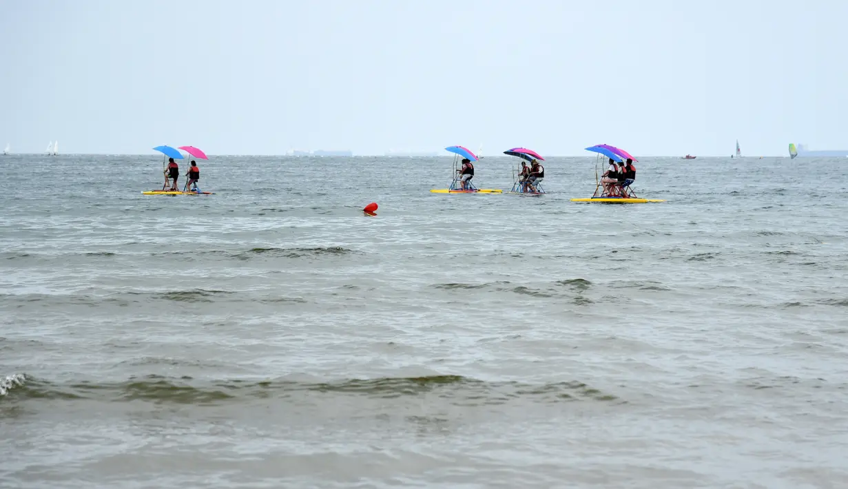 Pengunjung menaiki perahu saat menikmati waktu bersantai di sebuah pantai di Rizhao, Provinsi Shandong, China timur (9/7/2020). (Xinhua/Wang Kai)