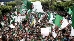 Demonstran memegang bendera dan spanduk saat berunjuk rasa di Aljir, Aljazair, Jumat (19/4). Demonstran kembali turun ke jalan-jalan untuk mendesak perubahan demokrasi besar-besaran melampaui pengunduran diri mantan presiden Abdelaziz Bouteflika. (REUTERS/Ramzi Boudina)