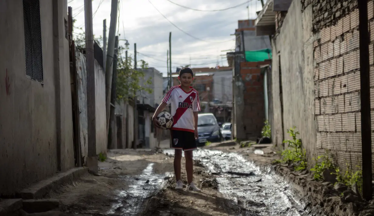 Daniel Dorado dari Argentina mengenakan jersey River Plate berpose di dekat rumahnya di daerah kumuh Costa Eperanza, Buenos Aires, 12 September 2020. Daniel, 12, yang bersekolah di sekolah sepak bola Angel Labruna bermimpi menjadi pemain sepak bola di klub River Plate. (ARIEL TIMY TORRES/AFP)