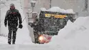 Seorang pria dan sebuah bus mencoba berjalan di jalan yang tertutup salju tebal di Berchtesgaden, Jerman, Kamis (10/1). (Tobias Hase/dpa/AFP)