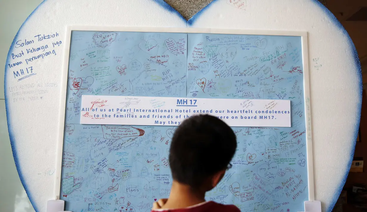 Seorang anak melihat-lihat pesan belasungkawa bagi para korban jatuhnya pesawat Malaysia Airlines MH-17 yang dipajang di Kuala Lumpur, (20/7/2014). (REUTERS/Olivia Harris)