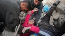 Anggota Syrian Civil Defence atau White Helmets berusaha menyelamatkan gadis yang tertimpa puing bangunan usai serangan udara pasukan pemerintah di Desa Tal Mardikh, Provinsi Idlib, Suriah, Kamis (19/12/2019). Pasukan Suriah kian intens menyerang Idlib. (Omar HAJ KADOUR/AFP)