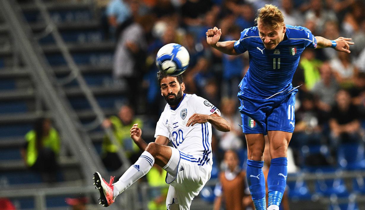 Striker Italia, Ciro Immobile, duel udara dengan gelandang Israel, Marwan Kabha, pada laga kualifikasi Piala Dunia 2018 di Stadion Reggio Emilia, Italia, Selasa (5/9/2017). Italia menang 1-0 atas Israel. (AFP/Vicenzo Pinto)