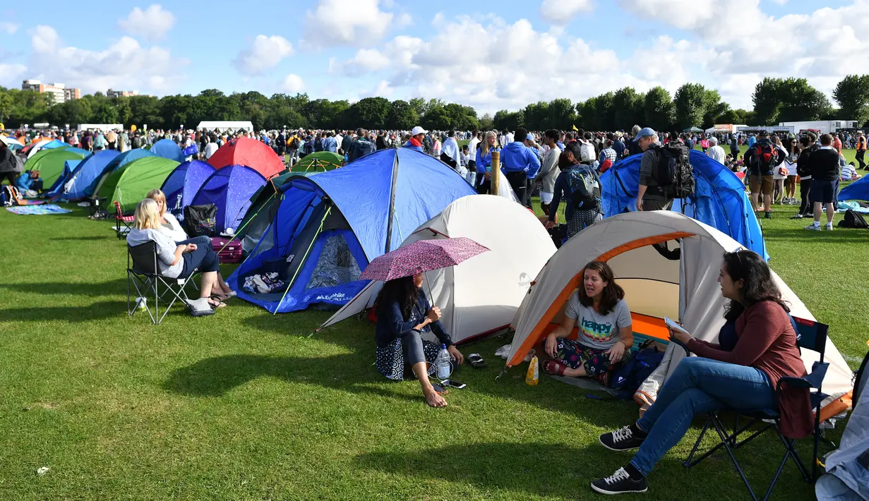 Sejumlah penonton beristirahat di tenda ketika mengantre untuk membeli tiket pada hari pertama turnamen tenis Kejuaraan Wimbledon 2019 di The All England Tennis Club di Wimbledon, London barat daya (1/7/2019). Turnamen ini dimulai 1 Juli-14 Juli 2019. (AFP Photo/Ben Stansall)