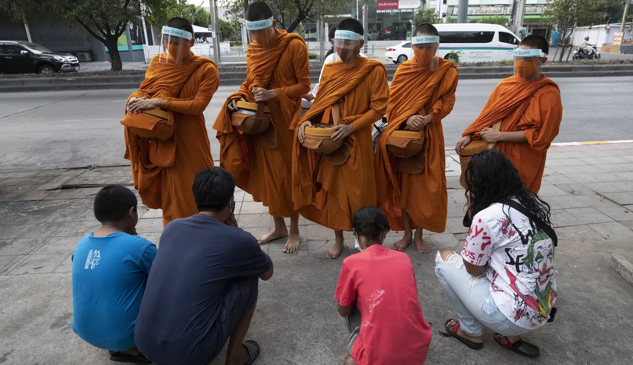Warga berdoa usai memberikan makanan kepada para biksu Buddha yang memakai pelindung wajah untuk melindungi diri dari virus corona COVID-19 saat mengumpulkan sedekah di Bangkok, Thailand, Selasa (31/3/2020). Hingga 30 Maret 2020, kasus positif COVID-19 di Thailand ada 1.524. (AP Photo/Sakchai Lalit)