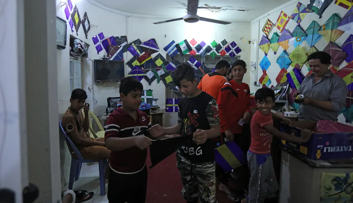 Sekelompok anak muda Irak membeli permainan tradisional layang-layang  selama bulan Ramadan di sebuah toko di Kerbala pada 12 Mei 2019. Bermain layang-layang merupakan salah satu cara muslim Irak untuk mengisi waktu sambil menunggu saat berbuka puasa (ngabuburit). (REUTERS/Abdullah Dhiaa Al-Deen)